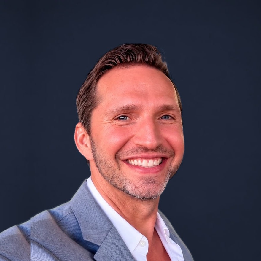 Noel Rosencranz, executive and leadership coach, in a grey jacket against a navy studio background